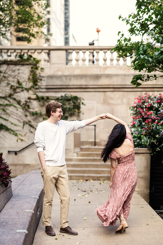 Couple dances on the Chicago Riverwalk during sunrise engagement session