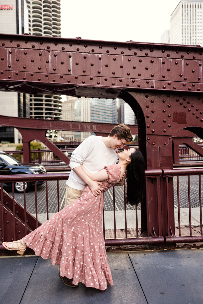 Man dips his partner on a bridge in downtown Chicago during sunrise engagement session