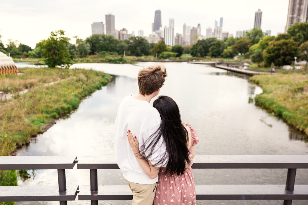 Couple looks out at a pond in Lincoln Park with Chicago skyline in the background