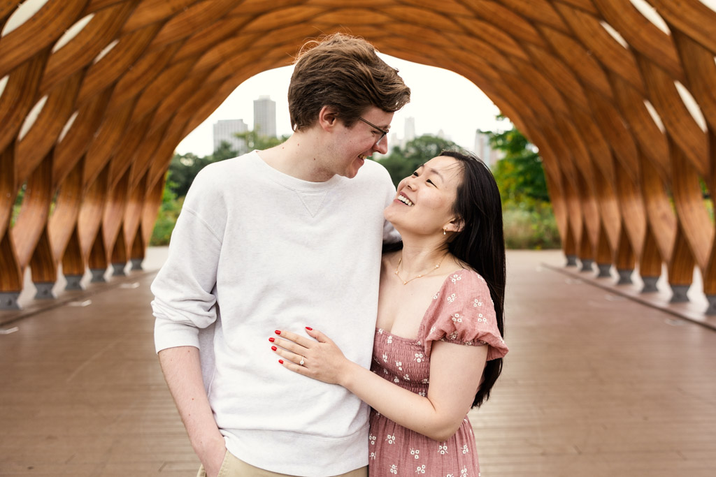 Happy engaged couple looks at each other as they stand under the Lincoln Park Honeycomb