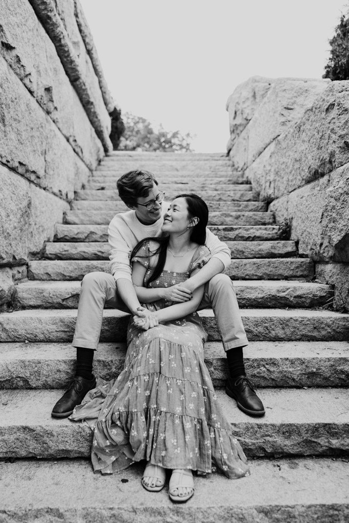 Black and white photo of happy couple sitting on stone stairs near the Ulysses S. Grant Monument during their sunrise Lincoln Park engagement session
