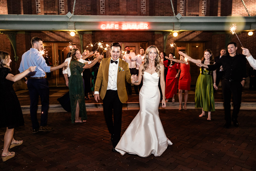 Bride and groom exit Cafe Brauer as guests light sparklers during their wedding reception