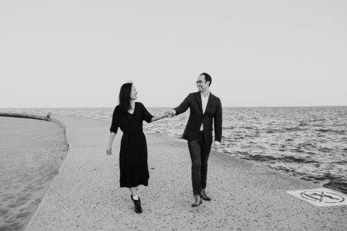 Black and white photo of couple holding hands strolling along Lake Michigan at North Avenue Beach during their Chicago fall engagement session