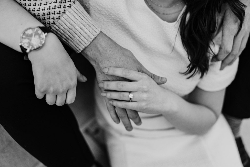Black and white photo of couple's hands during their fall engagement session, focused on the woman's ring