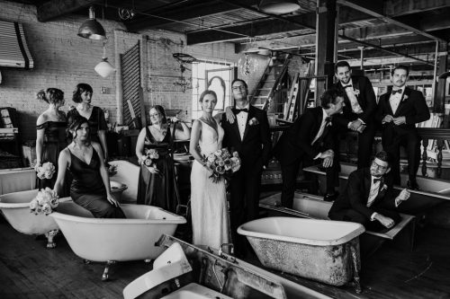 Creative wedding party photo standing in vintage bathtubs at Salvage One before September wedding ceremony