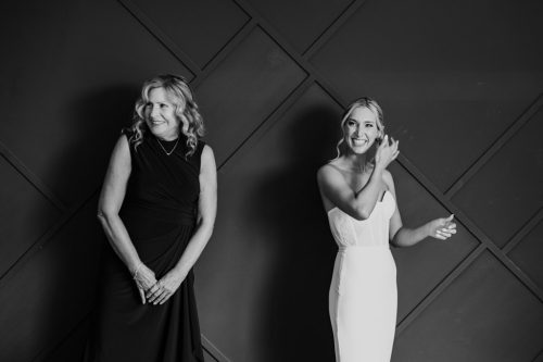Black and white photo of bride and her mother standing in front of geometric pattern wall