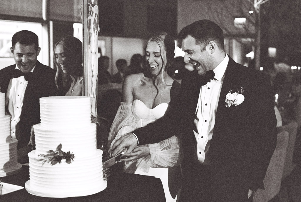 At the South Branch Tavern and Grille, a bride and groom are smiling as they cut their wedding cake together, creating a moment brimming with joy and love.