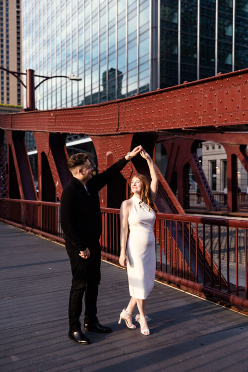 Couple dances on the Clark Street Bridge by the Chicago River, during their downtown engagement session