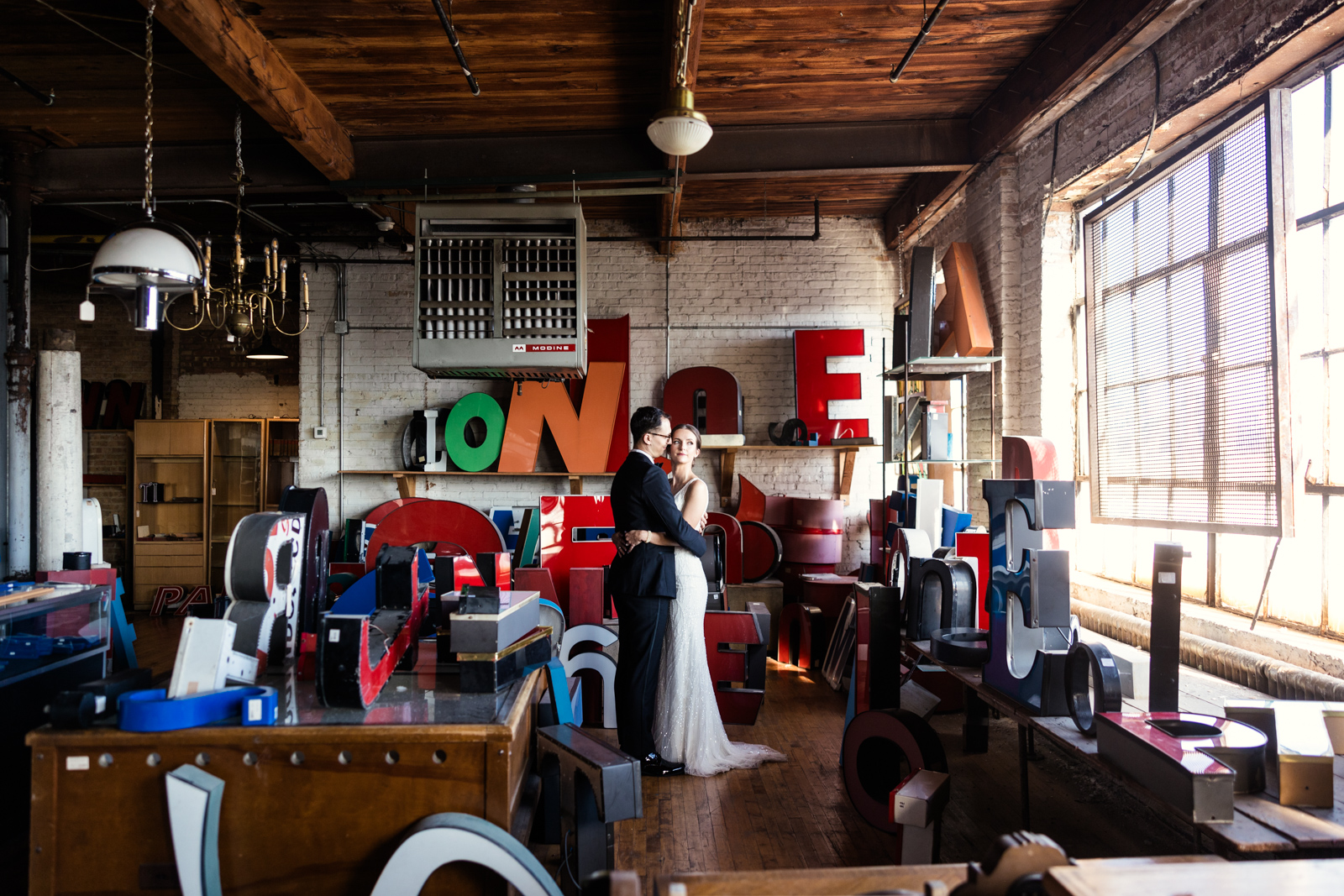 Romantic photo of bride and groom surrounded by marquee letters in storage space of Salvage One wedding venue