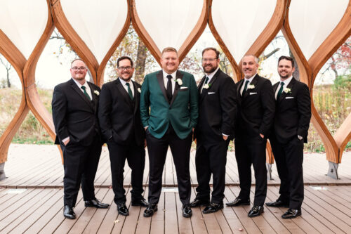 Wedding party photo of groom in green suit jacket and groomsmen in black inside Lincoln Park Honeycomb