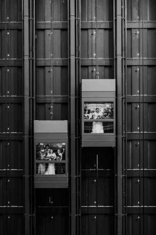 Creative black and white photo of wedding party in two glass elevators at Embassy Suites River North in downtown Chicago