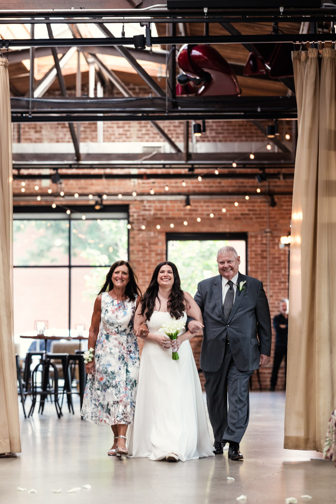 Bride walks down the aisle flanked by her parents at Ovation Chicago