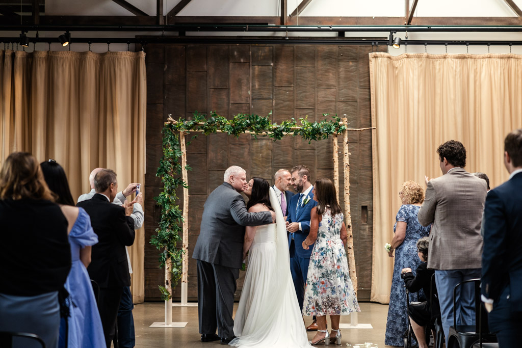 Bride and groom hug their families during their wedding ceremony at Ovation Chicago