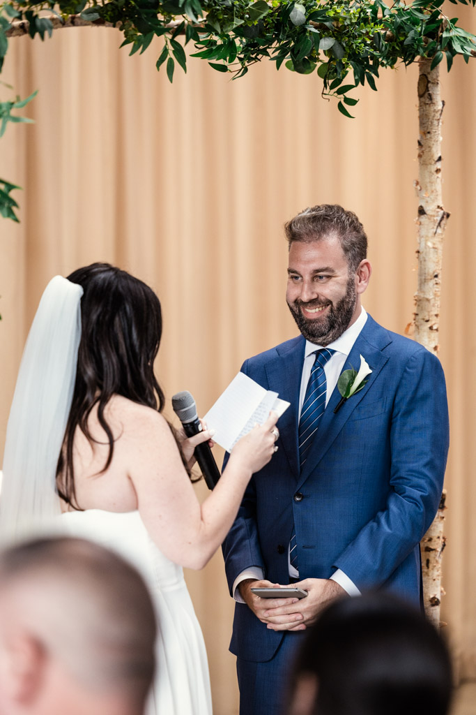 Bride reads vows to groom as they stand under the chuppah during their Ovation Chicago wedding ceremony.