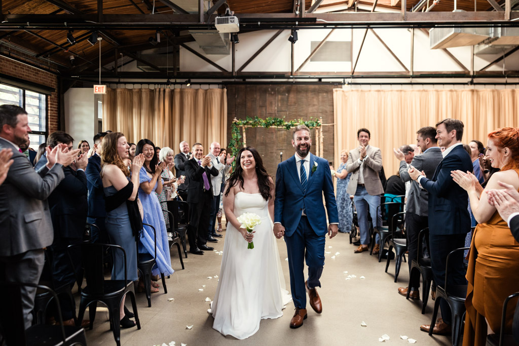 Happy bride and groom walk down aisle at the end of their summer Ovation Chicago wedding ceremony