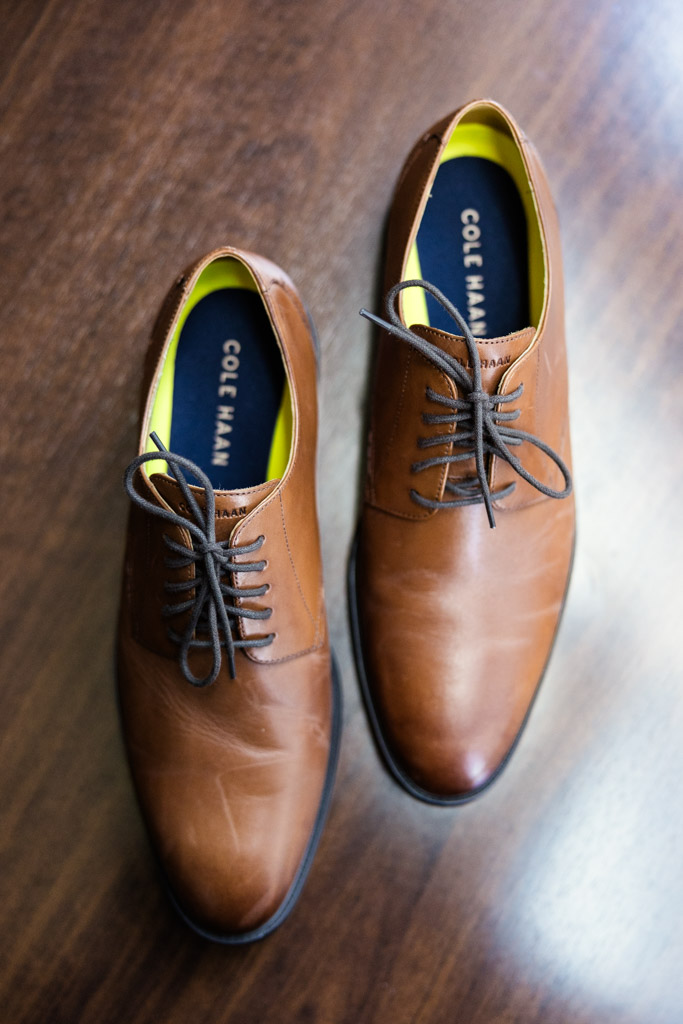 Groom's brown leather dress shoes with laces on a wooden floor