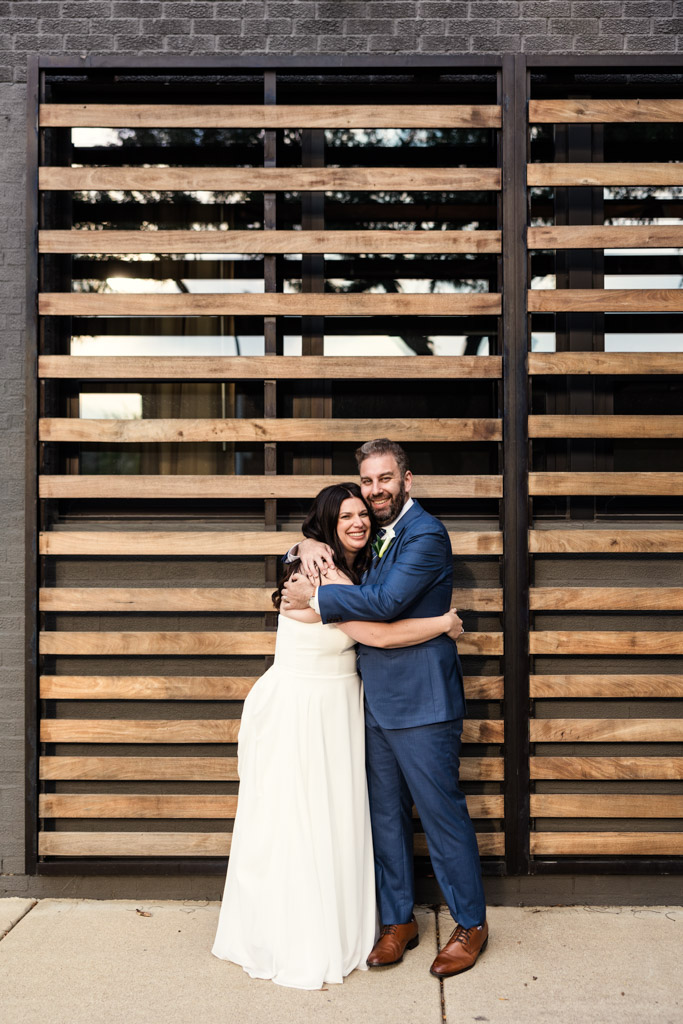 Portrait of bride and groom in front of a wooden slat wall outside Ovation Chicago wedding venue