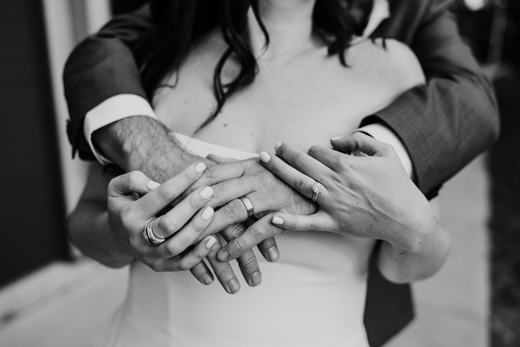 Black and white close-up photo of newlywed couple's hands adorned with rings outside Ovation Chicago wedding venue