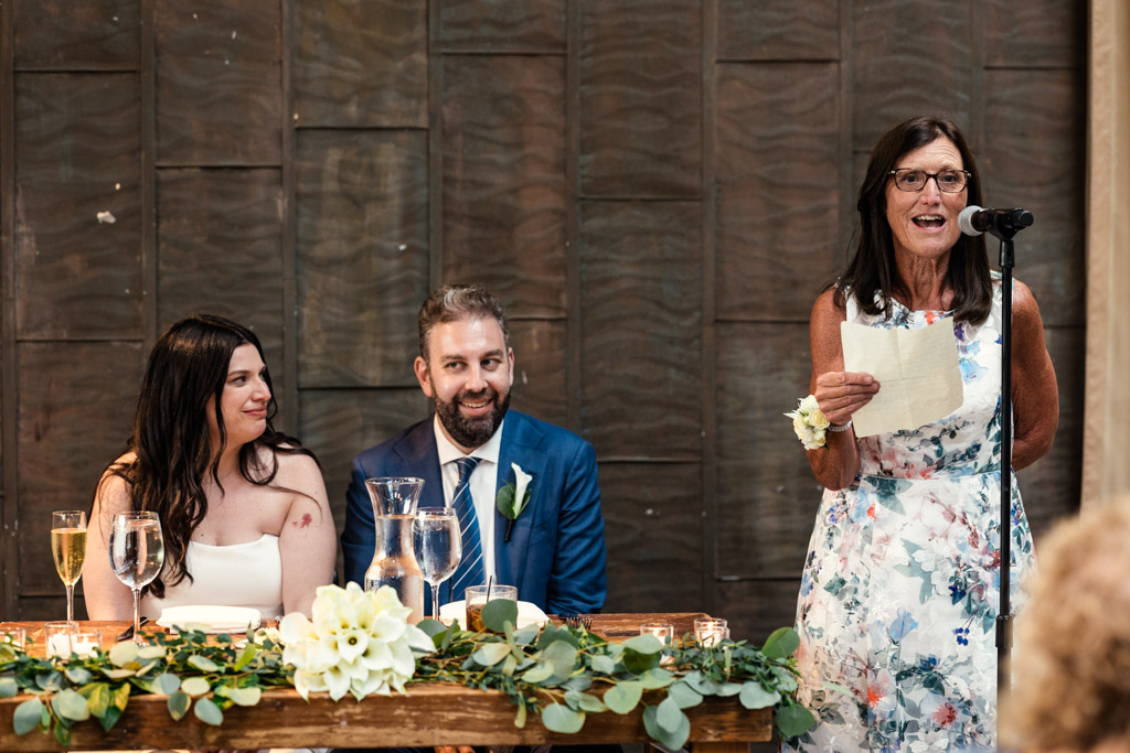 Woman gives speech at Ovation Chicago wedding reception while newlyweds listen