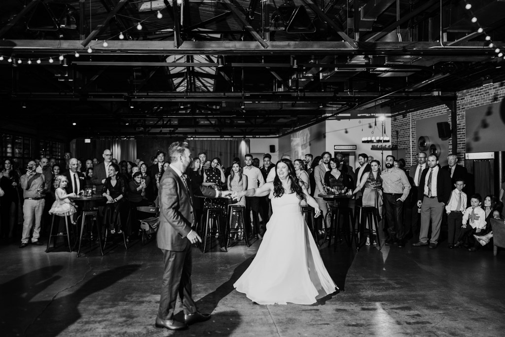Black and white photo of bride and groom during their first dance at Ovation Chicago surrounded by guests