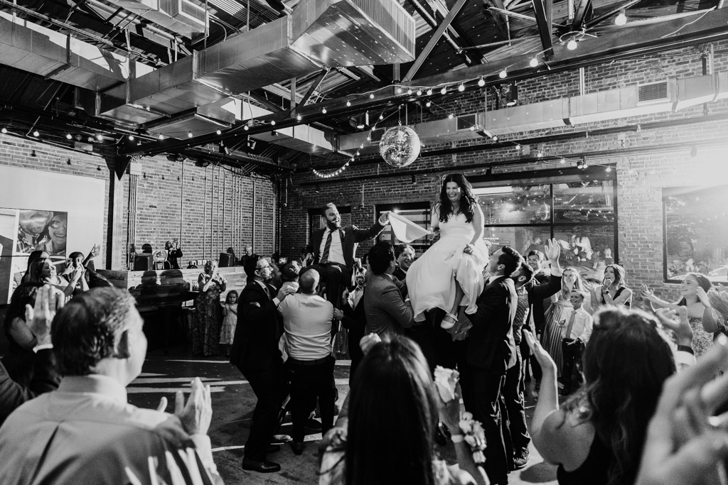 Newlywed couple is lifted on chairs during the Hora at their Ovation Chicago wedding reception