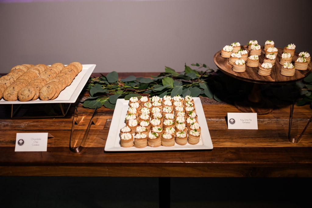 Three platters of desserts on a wooden table, featuring cookies and cream-topped pastries for Ovation Chicago wedding reception