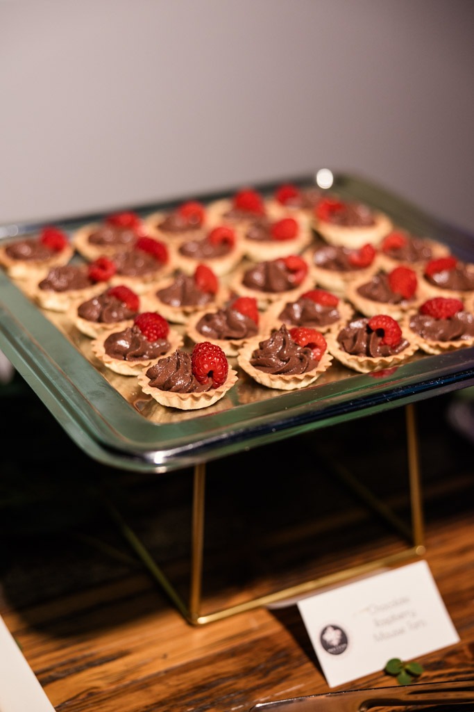 Miniature chocolate tarts topped with raspberries arranged on a glass tray for Ovation Chicago wedding reception