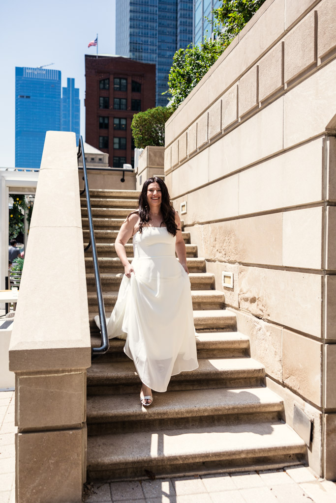 Bride walks down staircase toward the groom during their first look on the Chicago Riverwalk