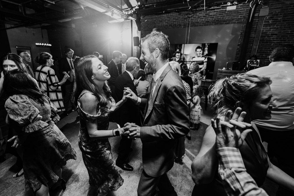 Black and white photo of a joyful couple dancing surrounded by other guests during Ovation Chicago wedding reception