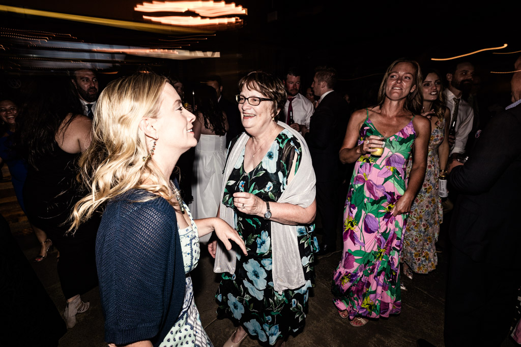 Guests wearing colorful dresses and smiling on the dance floor during Ovation Chicago wedding reception
