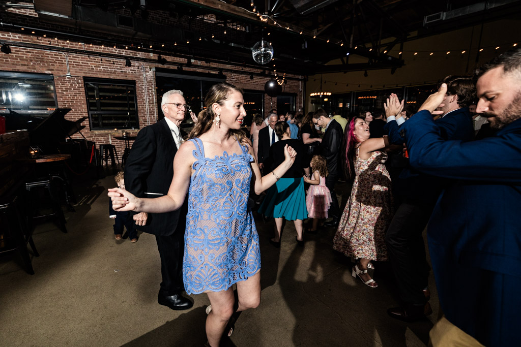 Woman in a blue dress and other guests on the dance floor during wedding reception at Ovation Chicago