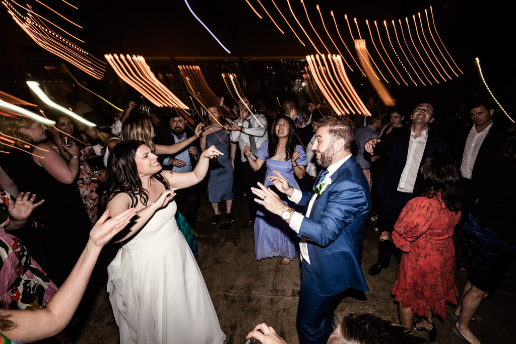 Bride, groom and guests dance during Ovation Chicago wedding reception twinkling string lights