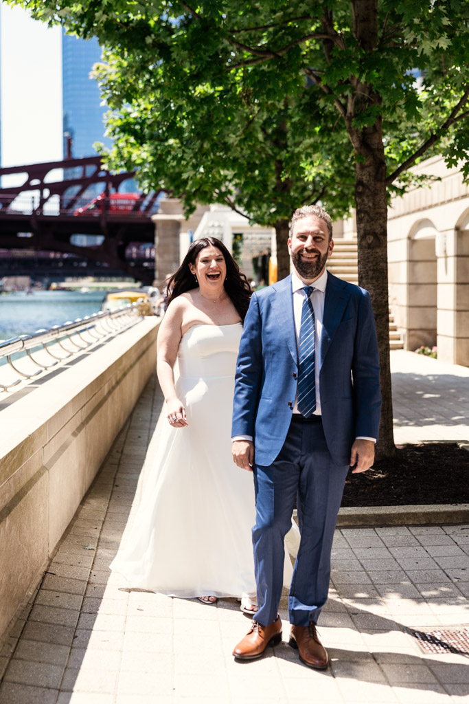 Bride approaches groom beaming with joy during their first look next to the Chicago River
