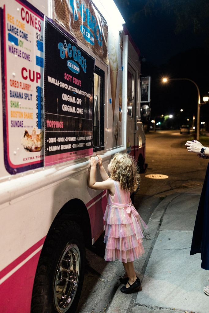 A child in a pink dress stands on tiptoes, to receive ice cream from the Big Bro's ice cream truck during Ovation Chicago wedding reception