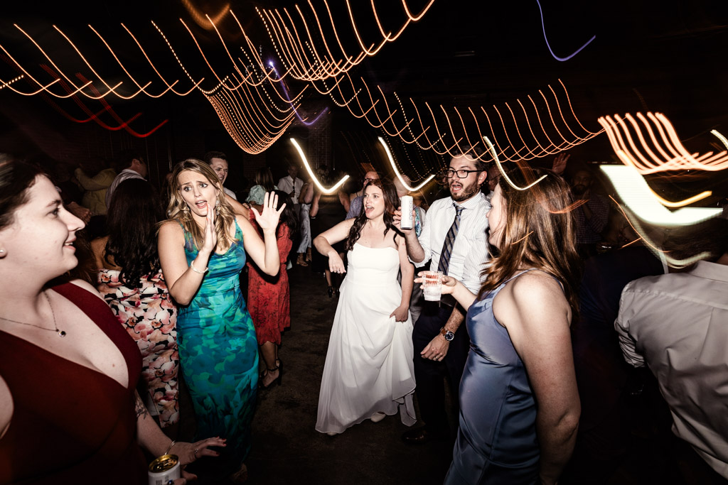 Bride and guests dance with motion blur and colorful light trails overhead during wedding reception at Ovation Chicago