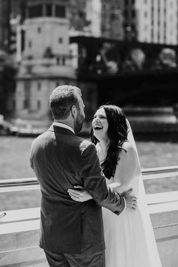 Black and white photo of bride and groom laughing on the Chicago Riverwalk