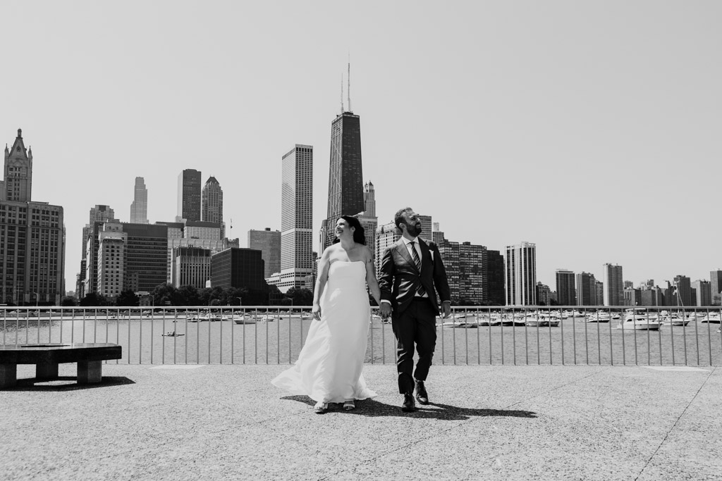 Black and white photo of bride and groom on the lakefront with downtown Chicago buildings in the background before their wedding celebration at Ovation Chicago
