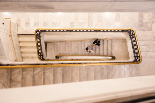 Creative photo of brides ascending a spiraling marble staircase in San Francisco City Hall