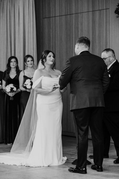 Black and white photo of bride and groom exchanging rings at their Sarabande Chicago wedding