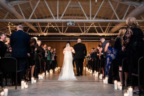 Photo of bride walking down candlelit aisle with her father during Sarabande Chicago wedding ceremony