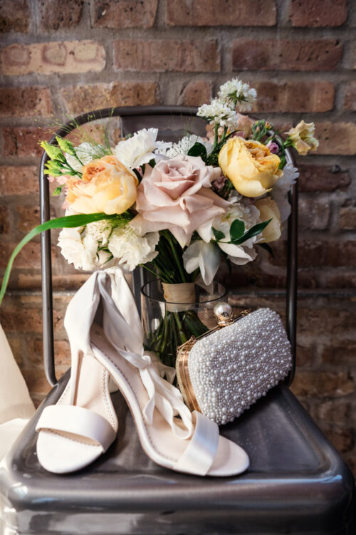 Bride's bouquet, shoes and purse sit on metal chair at The Hive on Hubbard wedding venue in Chicago