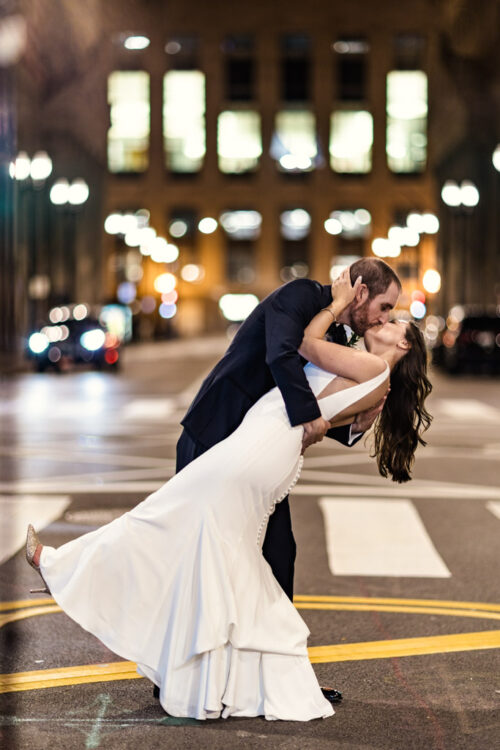 Romantic photo of newlyweds kissing on LaSalle Street at night outside The Library at 190 in downtown Chicago