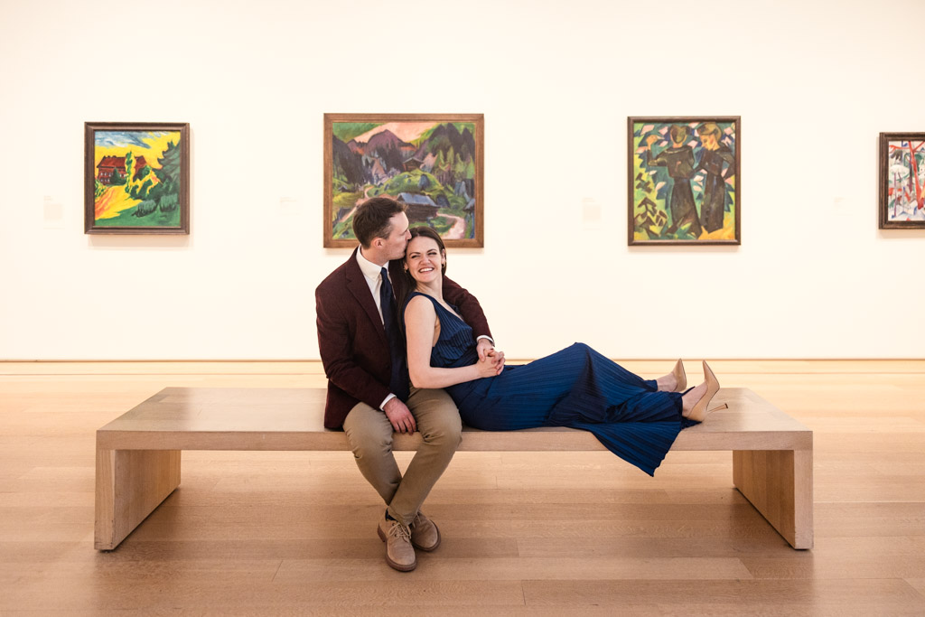 Candid photo of engaged couple on a bench in a gallery of the Art Institute of Chicago