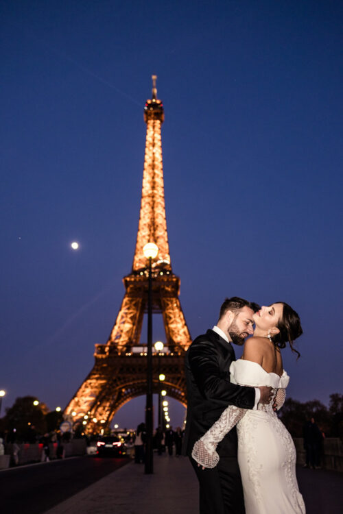 A couple embraces in wedding attire at night, celebrating their unforgettable Eiffel Tower wedding against the backdrop of Paris’s glowing landmark.