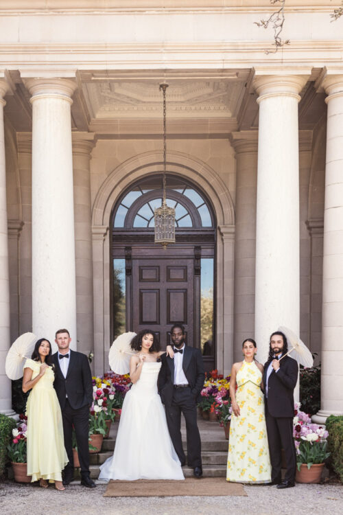 Wedding party poses outside Filoli Historic House holding parasols