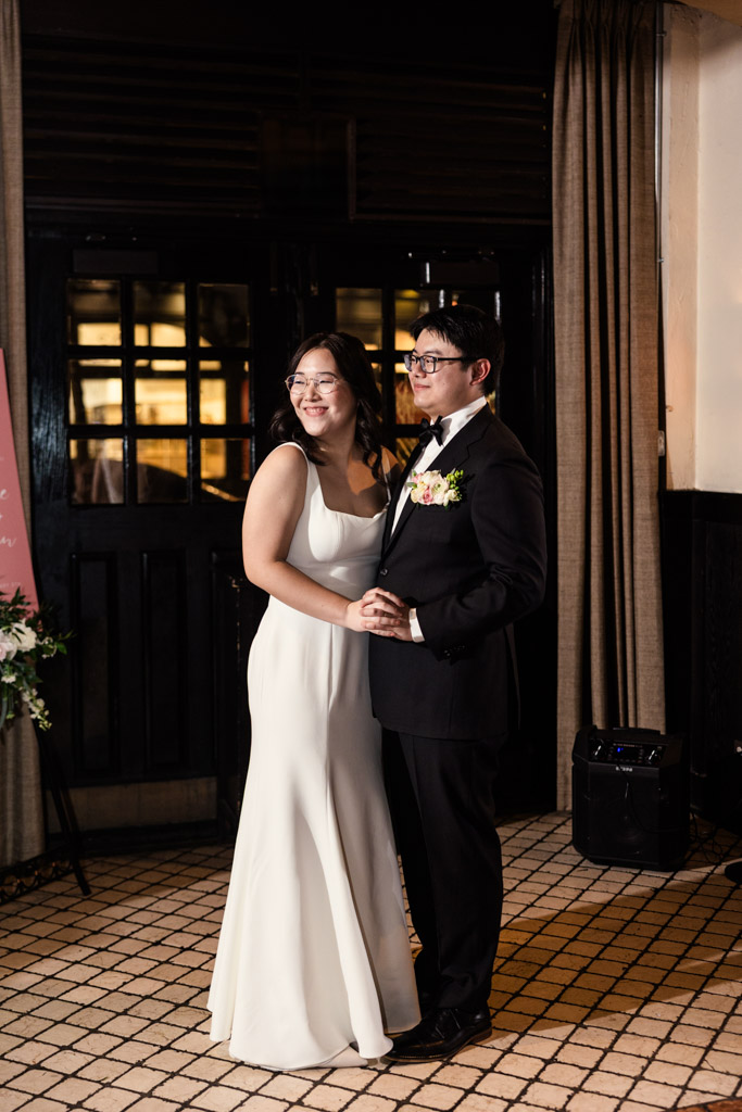 A bride and groom smile and dance together indoors at their Chicago winter wedding reception.