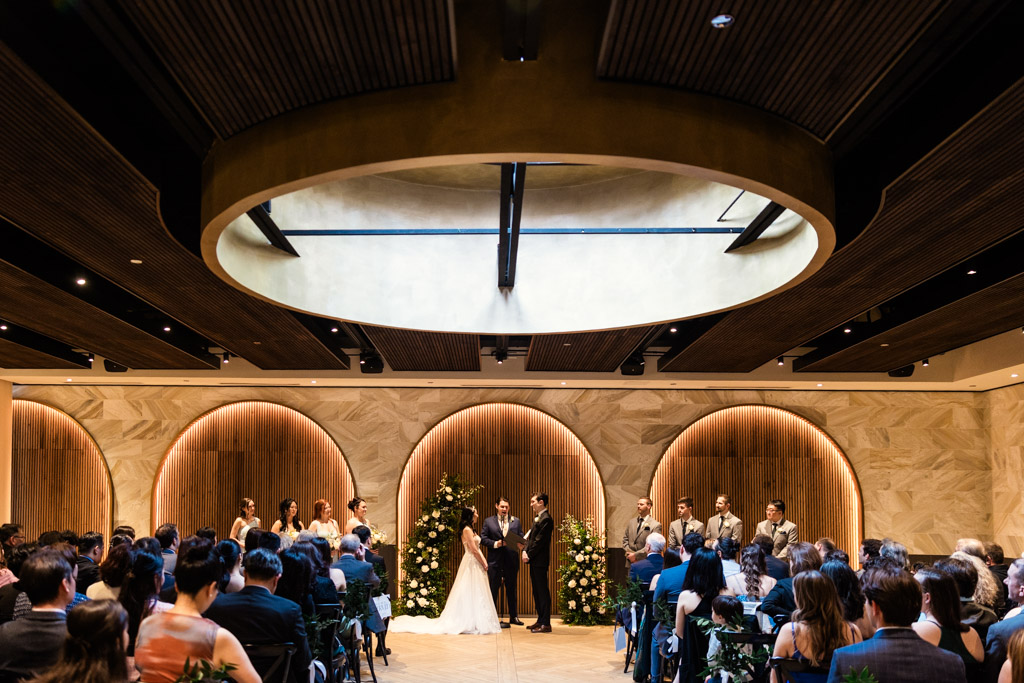 Wedding ceremony at Chicago Winery with the bride and groom at the front of the space, surrounded by guests and floral decorations