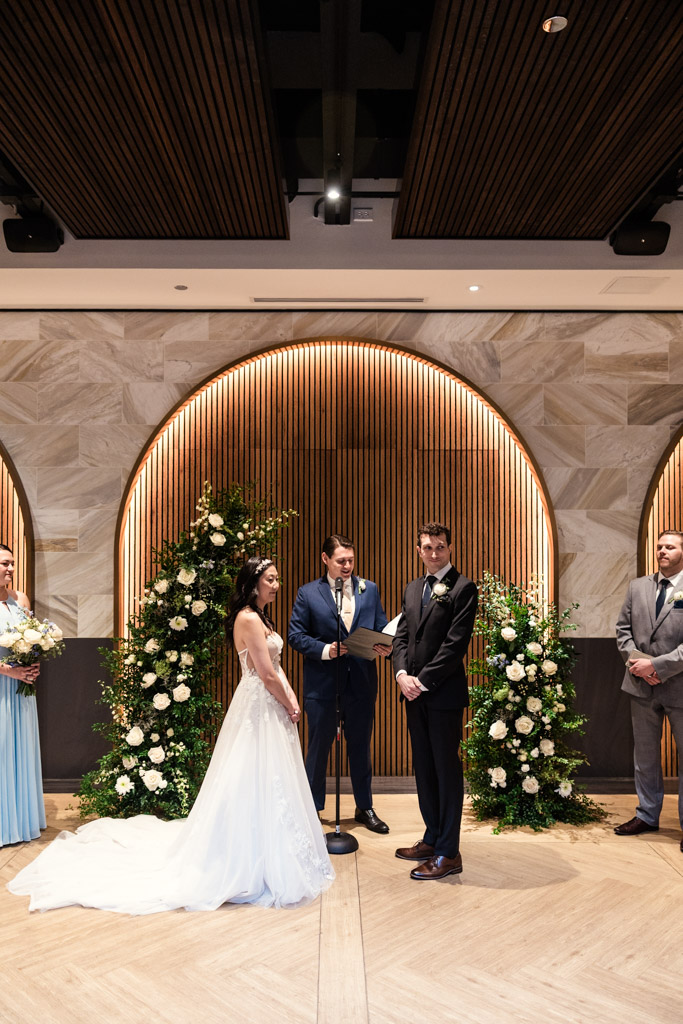 Bride and groom look at their guests with an officiant standing behind them during wedding ceremony at Chicago Winery