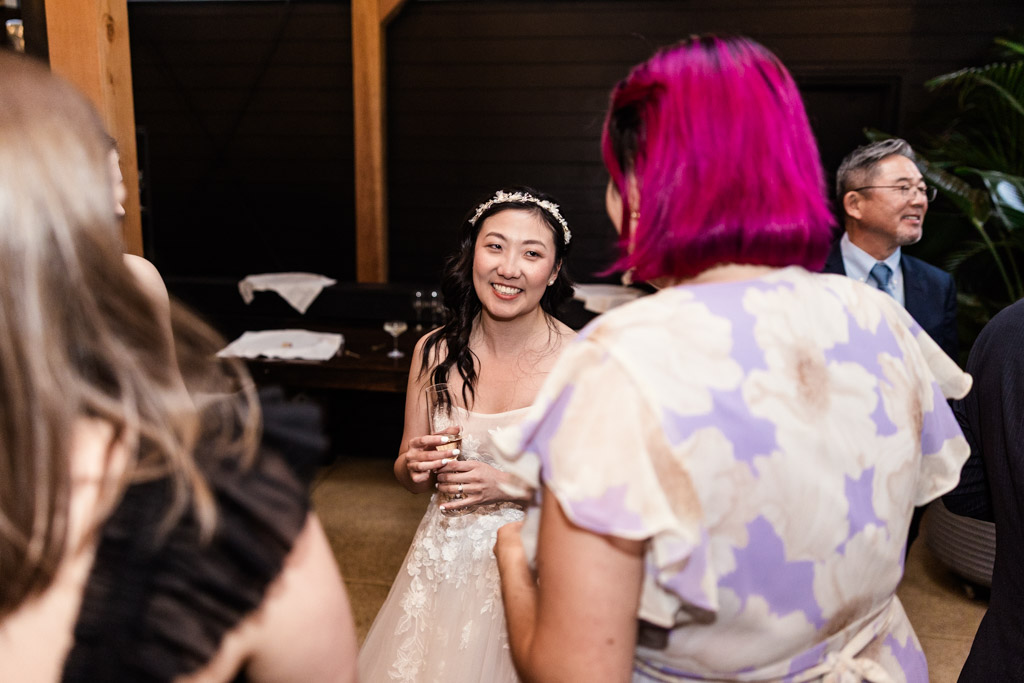 Bride in a white dress smiles while talking to guests at her wedding reception at Chicago Winery