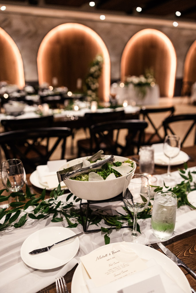 A salad bowl with serving tongs sits on an guest table for wedding reception at Chicago Winery